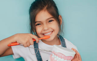 little girl smiling after brushing her teeth from floss boss